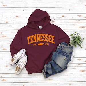 May include: Burgundy hooded sweatshirt with an orange graphic print of the state of Tennessee and the text "Tennessee Est. 1796".