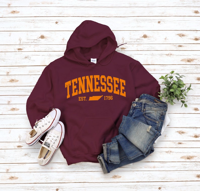 May include: Burgundy hooded sweatshirt with an orange graphic print of the state of Tennessee and the text "Tennessee Est. 1796".