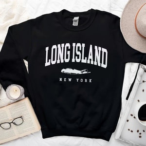 K&ouml;nnte beinhalten: Schwarzer Pullover mit wei&szlig;em Text "Long Island, New York" und einer wei&szlig;en Umrandung von Long Island.