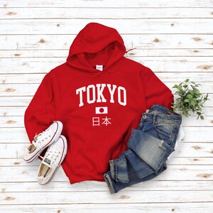 May include: Red hooded sweatshirt with white text that says "TOKYO" and a Japanese flag with the text "日本" underneath.