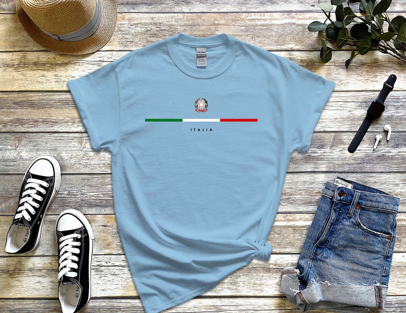 Puede incluir: Camiseta azul claro con una franja verde, blanca y roja a trav&eacute;s del pecho. La franja presenta el escudo de armas italiano y la palabra "ITALIA" debajo.
