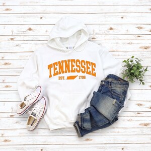 May include: White hooded sweatshirt with the text "Tennessee Est. 1796" in orange with an outline of the state of Tennessee in orange.