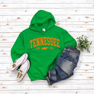 May include: Green hooded sweatshirt with the text "Tennessee Est. 1796" in orange with an outline of the state of Tennessee.