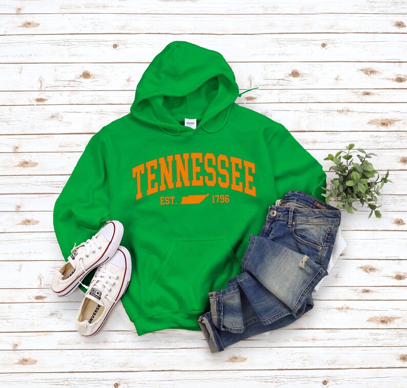 May include: Green hooded sweatshirt with the text "Tennessee Est. 1796" in orange with an outline of the state of Tennessee.