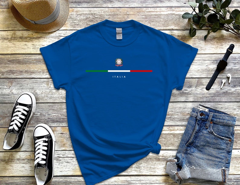 Puede incluir: Una camiseta azul real con una franja verde, blanca y roja a trav&eacute;s del pecho. La franja presenta un peque&ntilde;o emblema de la bandera italiana y la palabra "ITALIA" debajo.