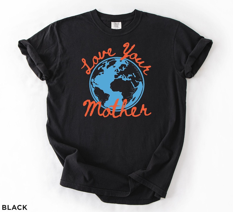May include: Black t-shirt featuring the phrase "Love Your Mother" in orange script, surrounding a blue and black illustration of the Earth. The shirt has short sleeves and is made of a soft material.