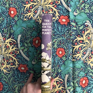 May include: A vintage paperback book titled "The Quest for the Perfect Planet" by Captain W.E. Johns. The cover features a purple background with a white moon and a stylized illustration of a mountain range.