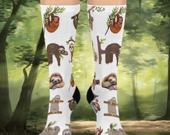 May include: A pair of white socks with a sloth pattern. The socks feature sloths in various poses, including hanging from branches and sleeping. The background of the socks is white with green leaves.