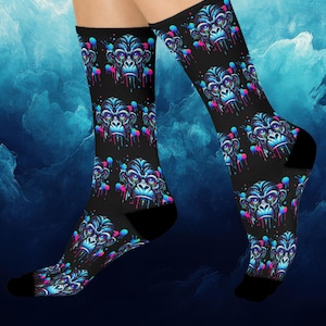 Könnte beinhalten: Schwarze Socken mit einem sich wiederholenden Muster eines farbenfrohen Gorillagesichts mit tropfendem Farbeffekt. Das Gesicht des Gorillas hat blaue, rosa und lila Akzente. Die Socken haben schwarze Fersen und Zehen.