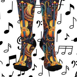 May include: A pair of knee-high socks featuring a vibrant musical instrument design. The socks display violins, trumpets, and other instruments in a colorful, abstract pattern against a dark blue background. Black heels and toes complete the design.