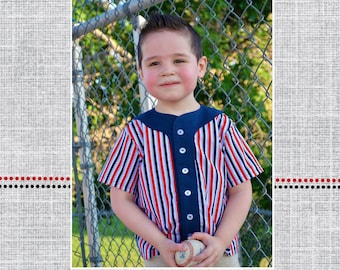 May include: A child wearing a red, white, and blue striped baseball jersey with a navy blue collar and buttons. The child is holding a baseball in their hands. The image is set against a chain link fence.