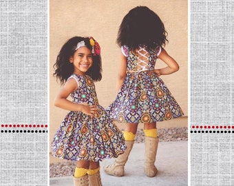 May include: Two girls wearing a blue and yellow patterned dress with a white lace-up back. The dress is called "Healanni's Corset Top/Dress" and is part of the "Polka Dot Umbrella" collection.