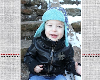 May include: A blue and white polka dot trapper hat with ear flaps. The hat is made of soft, fuzzy fabric and has a black leather patch with the text "Next Ames 1985 Club".