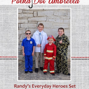 Może przedstawiać: Czterech dzieci przebranych za codziennych bohaterów. Policjant, lekarz, strażak i żołnierz. Stoją przed kamiennym murem. Tekst "Randy's Everyday Heroes Set" znajduje się na dole obrazu.