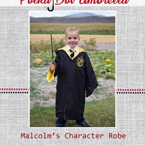 May include: A young boy wearing a black and yellow Hogwarts robe, holding a wand, and standing in a field. The robe has a crest on the chest and the text "Malcolm's Character Robe".