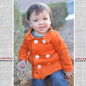 May include: A young child wearing an orange pea coat with white buttons. The child is sitting on a rock with a cup in their hand. The image is titled "Finn's Pea Coat".