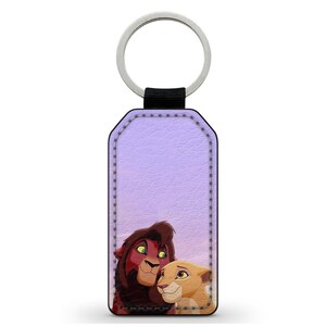 Op de afbeelding: Een paarse leren sleutelhanger met een afbeelding van Simba en Nala uit The Lion King.
