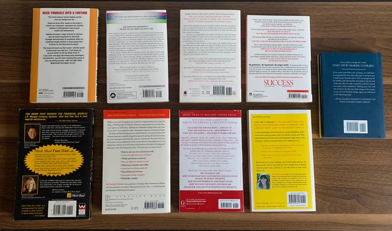 Pu&ograve; includere: Copertine posteriori di dieci diversi libri tascabili su una superficie di legno. I libri sono di colori diversi e hanno titoli diversi. Alcuni dei titoli includono "Leggi te stesso in una fortuna", "Pap&agrave; ricco, pap&agrave; povero", "Successo" e "Tu sei un marchio".