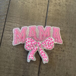 May include: Pink glitter "MAMA" sign with a pink and white leopard print bow.