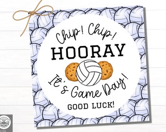 Pode incluir: Um círculo branco com o texto "Chip! Chip! HOORAY It's Game Day! GOOD LUCK!" e uma bola de voleibol e dois biscoitos. O círculo é rodeado por um padrão de bolas de voleibol brancas.