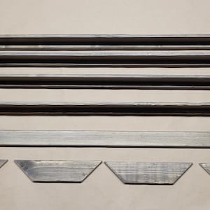 May include: A set of wooden shelves with brackets. The shelves are unfinished and have a natural wood color. The brackets are made of metal and have a silver finish.