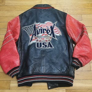 May include: A black and red leather varsity jacket with a large "Avirex USA" patch on the back. The patch features a stylised American flag and an eagle.