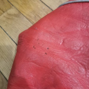 May include: Close-up of a red leather surface with small black dots.