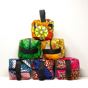 May include: Six colorful fabric zippered pouches with black handles. The pouches are stacked in a pyramid shape. The pouches have different patterns and colors, including green, orange, blue, pink, and red.