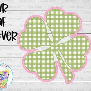 May include: A green four-leaf clover with a pink outline. The clover is made of a checkered pattern.