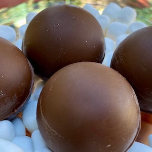 Peut inclure: Quatre boules de guimauve enrob&eacute;es de chocolat, &eacute;galement appel&eacute;es guimauves enrob&eacute;es de chocolat, sont dispos&eacute;es sur un lit de guimauves blanches.