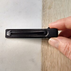Peut inclure: Une pince &agrave; cheveux en m&eacute;tal noir avec une surface textur&eacute;e.