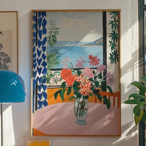 Cuadro de Matisse, mesa rosa, jarrón de flores, ventana frontal con vistas al mar, follaje colorido, motivos azules y blancos, techo blanco.