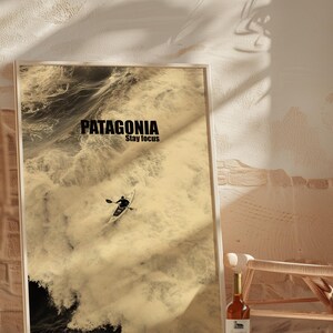 A paddler navigating rough ocean waves in a retro sepia tone. The phrase Patagonia Stay Focus highlights concentration and adventure. Perfect for water sports lovers and those seeking wilderness-inspired decor.