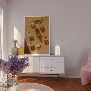 May include: A white cabinet with three drawers and gold handles sits on a wood floor. A white lamp with a gold arch sits on top of the cabinet. A vase with purple flowers sits on a pink round table in front of the cabinet. A framed print with the text "Either Again" hangs on the wall behind the cabinet.