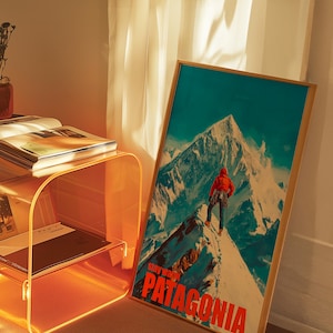 A striking poster featuring a climber in bright orange gear standing on a snowy mountain peak in Patagonia. This adventurous design captures the spirit of exploration and the beauty of the outdoors, perfect for nature lovers and thrill seekers.