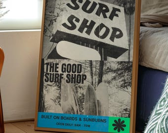 以下が含まれることがあります： 「SURF SHOP」の文字が上部に、その下に「THE GOOD SURF SHOP」と書かれた、額縁に入った白黒ポスター。ポスターは木製のフレームで、下部にはテキストと花のグラフィックが入った青と緑のセクションがあります。