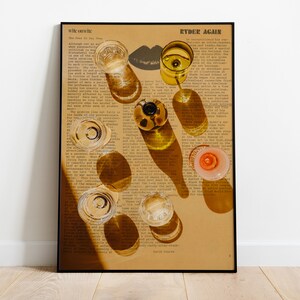 May include: A framed print of a vintage book page with a variety of glass bottles and glasses arranged on top. The bottles and glasses are casting shadows on the page. The text on the page reads "Ryder Again".