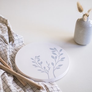 Könnte beinhalten: Ein rundes weißes Serviertablett mit einem blauen Blumenmuster. Das Tablett liegt auf einer karierten Tischdecke.