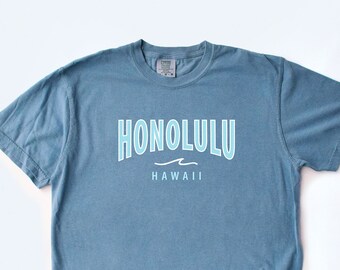 May include: A blue t-shirt with a white graphic that says "Honolulu, Hawaii" with a wave design.