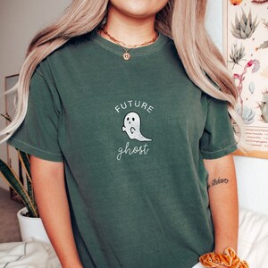 Könnte beinhalten: Ein grünes T-Shirt mit einem weißen Geistermotiv und dem Text "future ghost" auf der Vorderseite.
