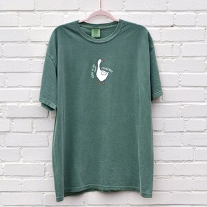 May include: A green t-shirt with a white goose graphic and the text "Honk if you're a chicken".