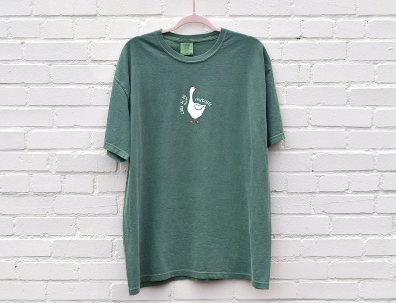 May include: A green t-shirt with a white goose graphic and the text "Honk if you're a chicken".