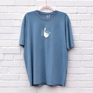 May include: A blue t-shirt with a white goose illustration and the text "Look at all the chickin'" printed on the front.