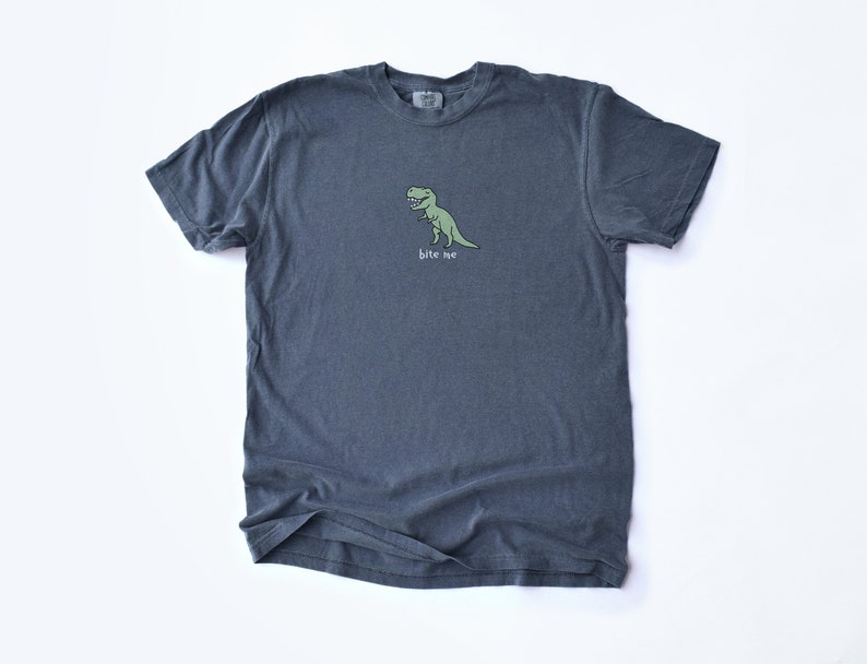 May include: A dark gray t-shirt with a green cartoon dinosaur and the text "bite me" printed on the front.