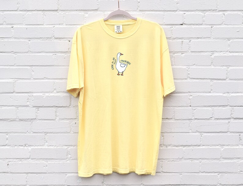 May include: A yellow short-sleeved t-shirt with a cartoon goose graphic and the text "Honk if you're a goose" printed on the front.