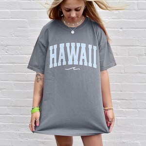 May include: A gray oversized t-shirt with a light blue "HAWAII" graphic and a small wave design underneath.