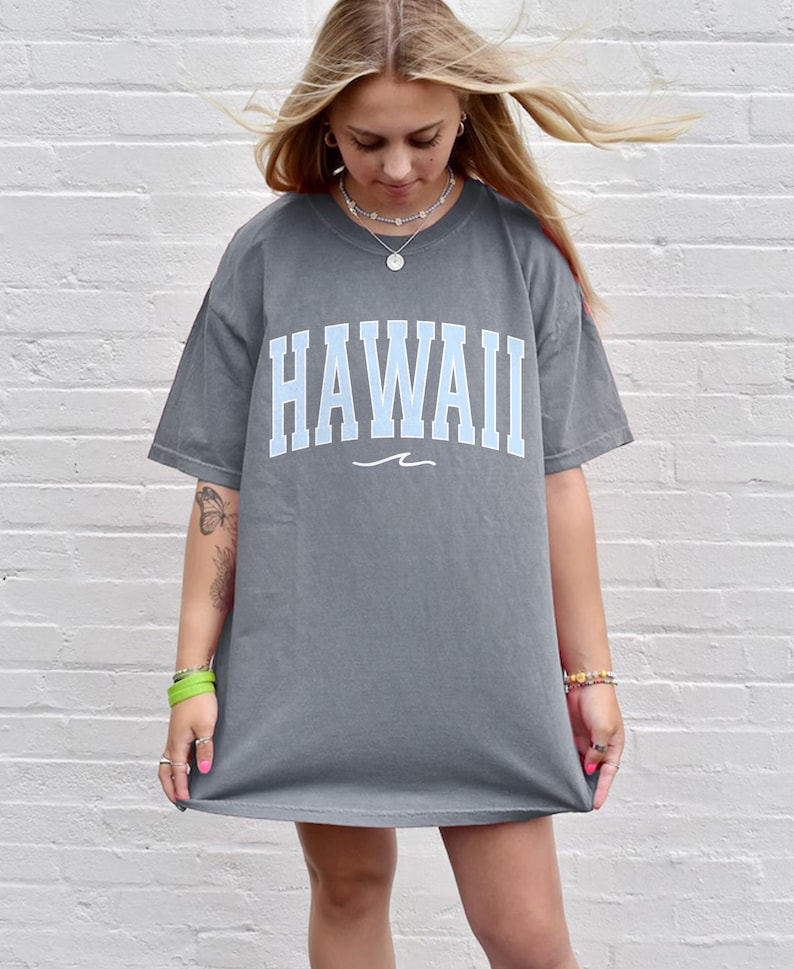 May include: A gray oversized t-shirt with a light blue "HAWAII" graphic and a small wave design underneath.