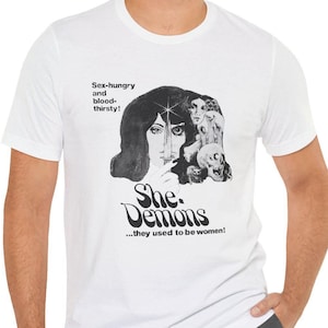 Puede incluir: Camiseta blanca con un estampado gráfico en blanco y negro de un rostro de mujer y el texto "She Demons...they used to be women!"