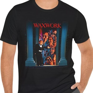 May include: A black t-shirt featuring a graphic of a man in a suit standing in front of a doorway with the text "WAXWORK" above him.