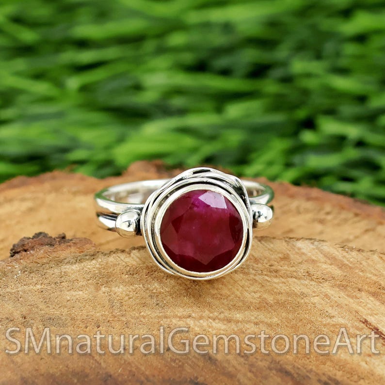 Puede incluir: Un anillo de plata con una piedra preciosa de rub&iacute; rojo oscuro engastada en una banda retorcida.